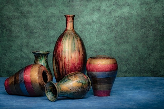 5 vases de poterie posées sur un drap bleu et le mur du fond est vert